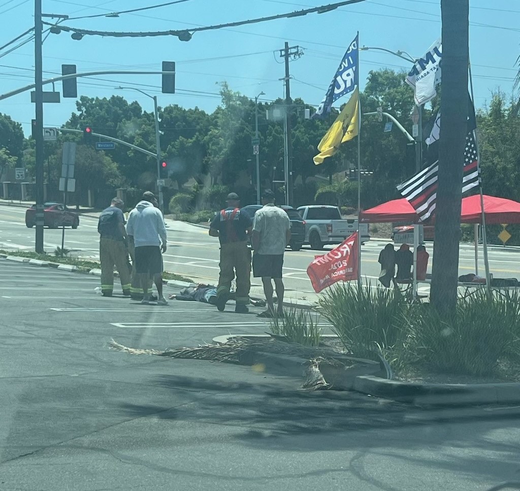 Several men standing over an injured person in the Smart & Final parking lot